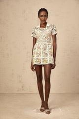 A short white mini dress with colorful floral embroidery patterns scattered across the fabric featuring a fitted waist and slightly puffed short sleeves