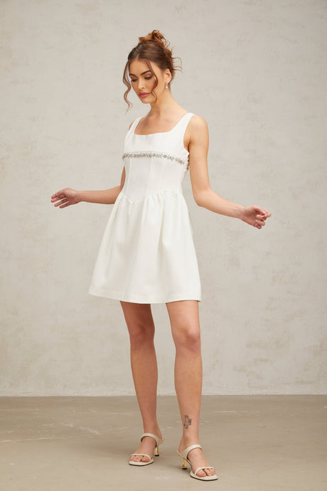 A short white mini dress with crystal embellishments adorning the fabric named Flavia