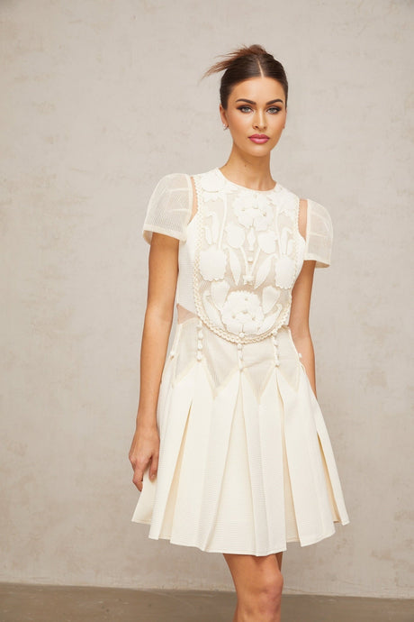 A short white mini dress with delicate flower embroidery details adorning the fabric