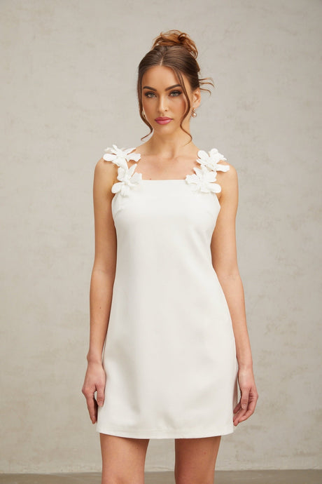 A short white mini dress with faux flower embellishments and a feminine silhouette named Clemence