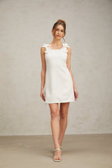 A short white mini dress with faux flower embellishments and a feminine silhouette