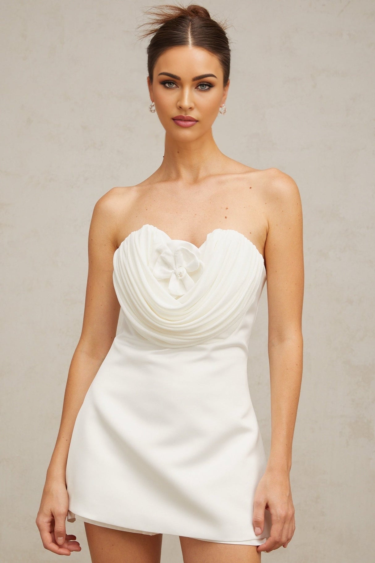 A short white mini dress with floral applique details on a model against a plain background