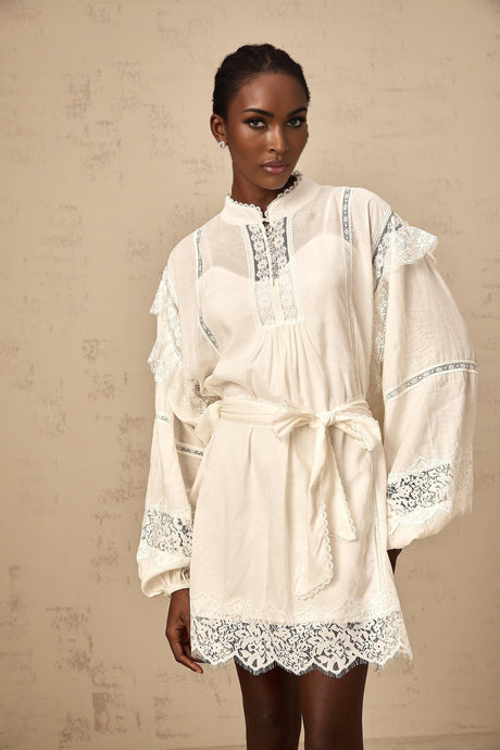 A short white mini dress with floral lace trim details and a feminine silhouette