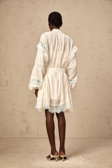 A short white mini dress with floral lace trim details featuring a delicate feminine design