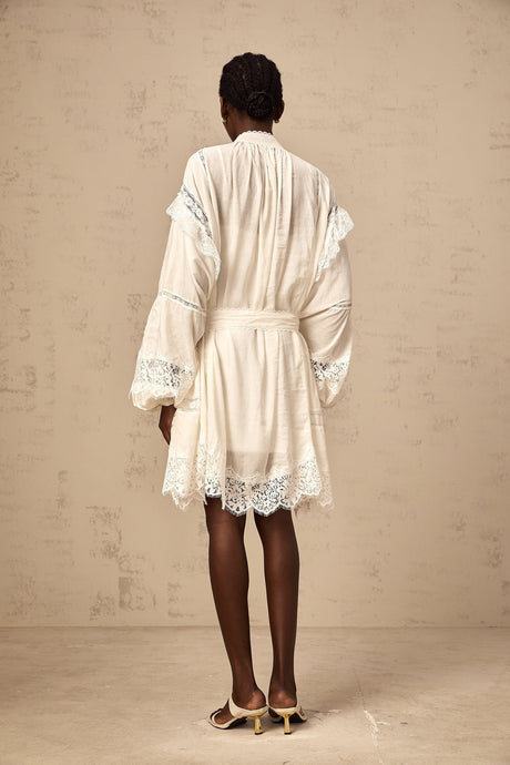 A short white mini dress with floral lace trim details featuring a delicate feminine design