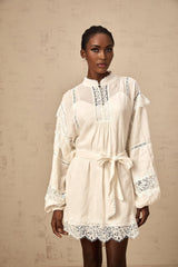 A short white mini dress with floral lace trim details shown on a model against a plain background