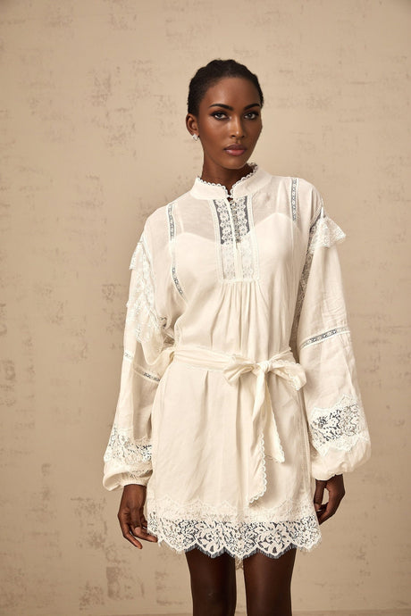 A short white mini dress with floral lace trim details shown on a model against a plain background