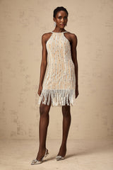 A short white mini dress with intricate embellishments and fringe detailing along the hem and sleeves