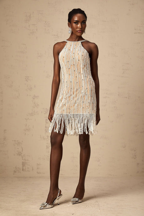 A short white mini dress with intricate embellishments and fringe detailing along the hem and sleeves