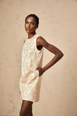 A short white mini dress with intricate embroidery and beaded embellishments featuring a fitted silhouette and delicate details