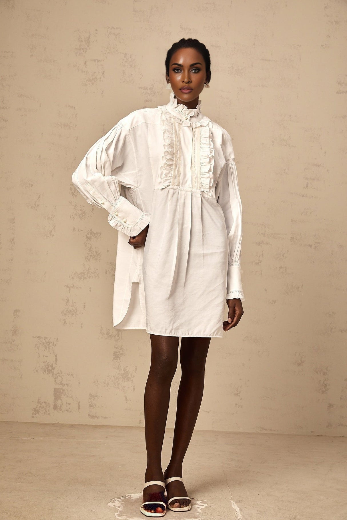 A short white mini dress with lace trim and ruffled details featuring a shirtstyle design and delicate feminine look