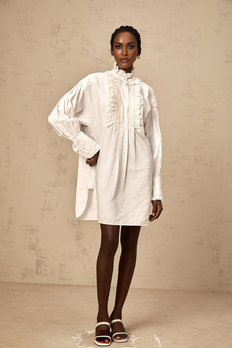 A short white mini dress with lace trim and ruffled details featuring a shirtstyle design and delicate feminine look