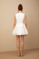 A short white mini dress with puff sleeves and tulle panelling featuring a fitted bodice and flared skirt