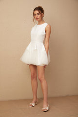A short white mini dress with puff sleeves and tulle panelling featuring a fitted bodice and flared skirt