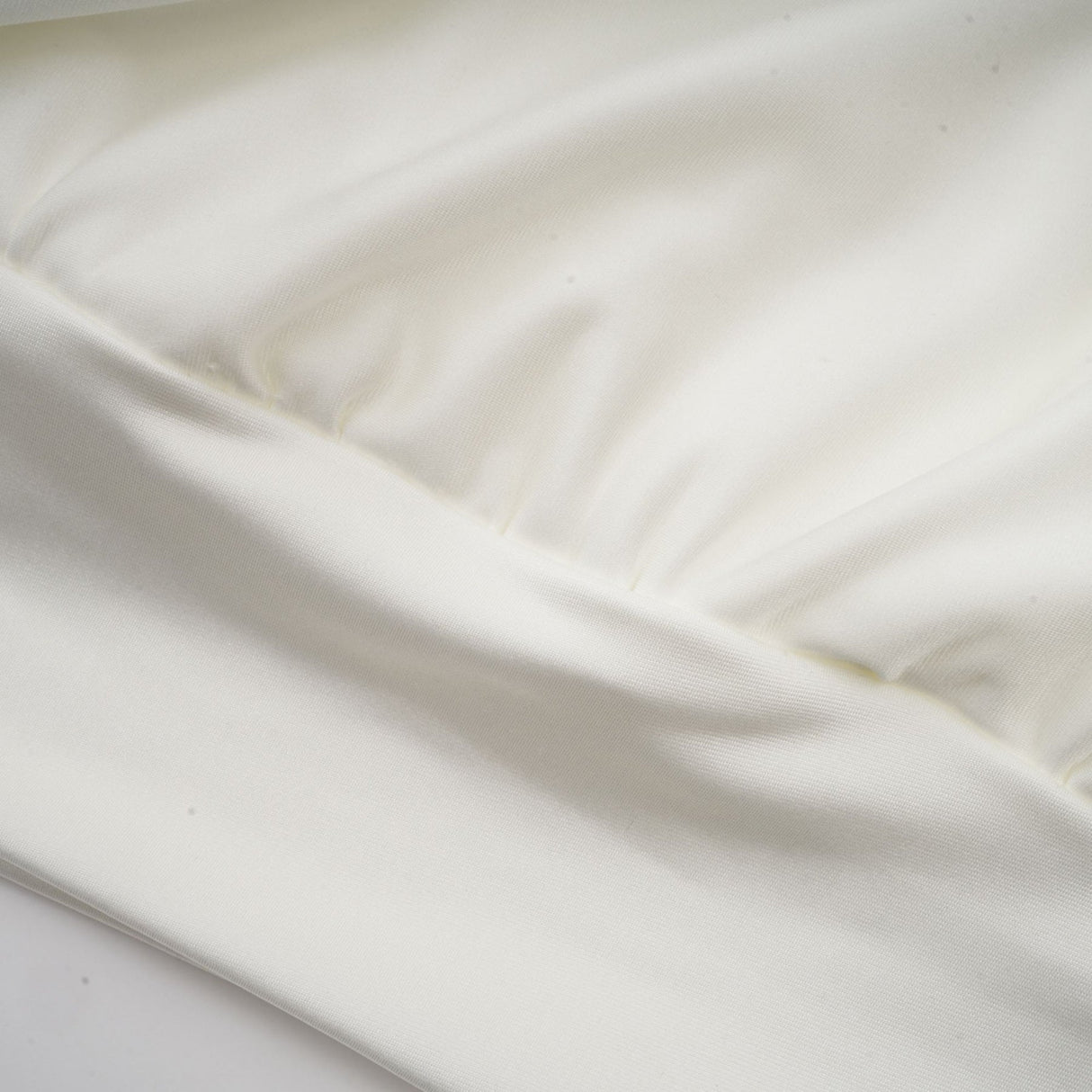 A short white mini dress with ruched detailing and faux flower embellishments