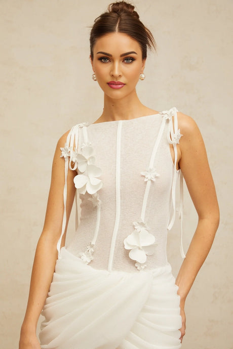 A short white mini dress with ruched fabric and floral applique details featuring a fitted silhouette and delicate floral embellishments