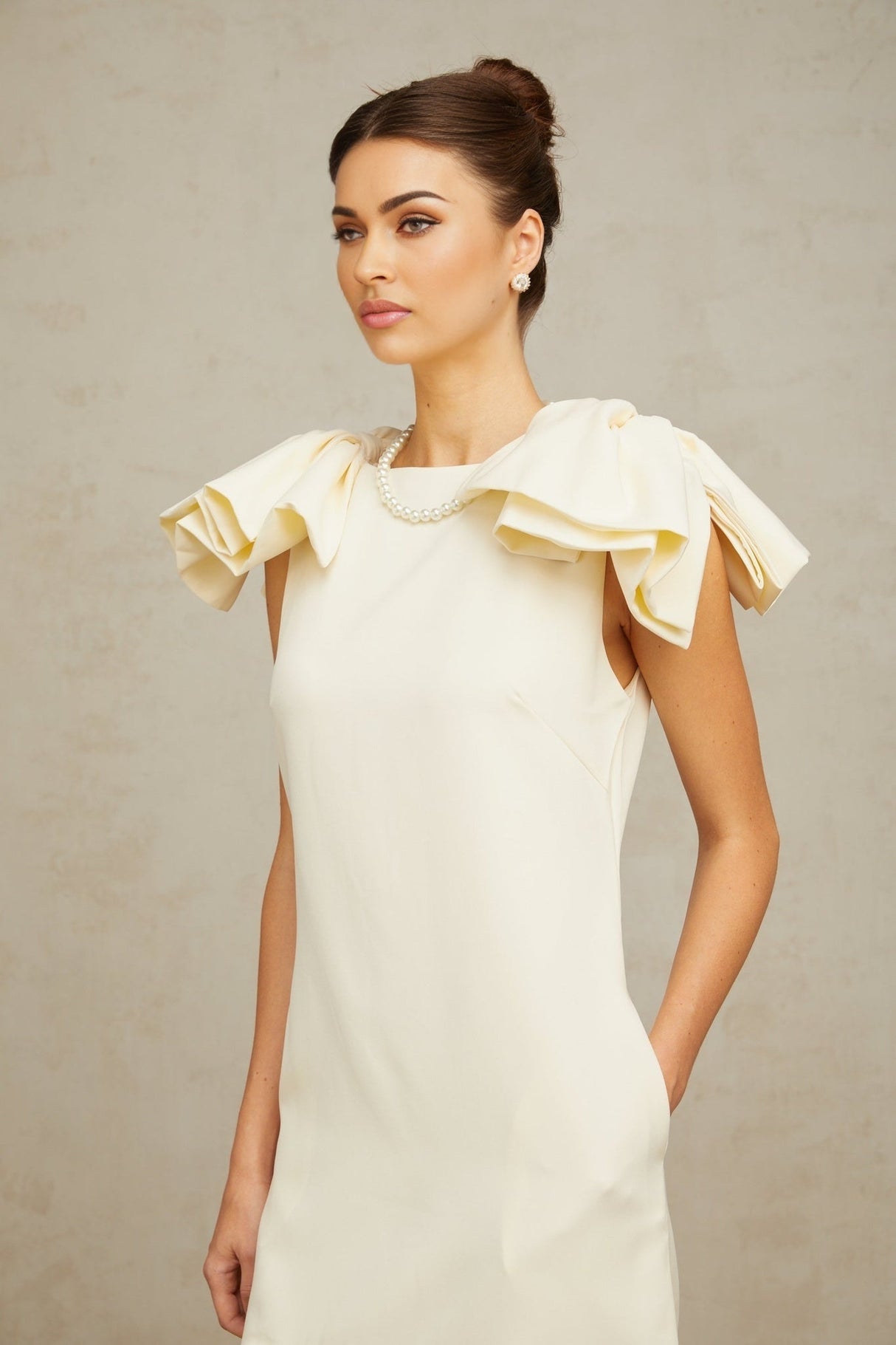 A short white mini dress with ruffled details and a prominent bow accent