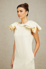 A short white mini dress with ruffled details and a prominent bow accent