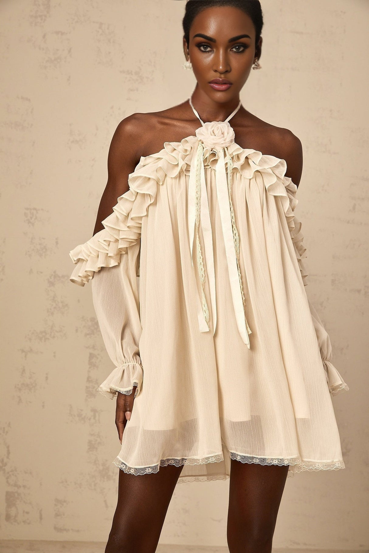 A short white mini dress with ruffled details and delicate floral appliques in neutral tones