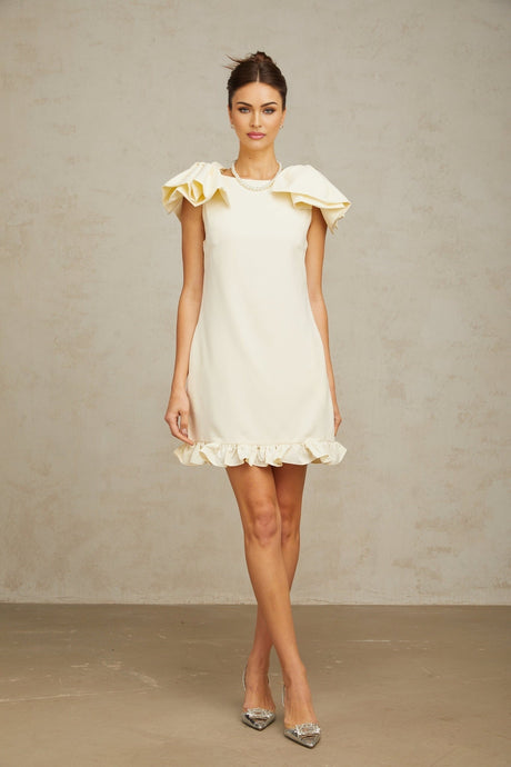 A short white mini dress with ruffles and a bow detail on the front
