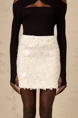 A short white mini skirt adorned with shimmering sequins covering the entire surface