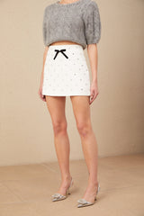 A short white mini skirt with a bow decoration and crystal embellishments named Gabrielle