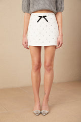 A short white mini skirt with a crystalembellished bow detail at the waist