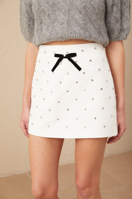 A short white mini skirt with a decorative bow and crystal embellishments named Gabrielle