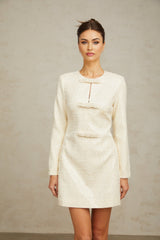 A short white tweed mini dress adorned with shimmering sequins featuring a fitted silhouette and intricate texture