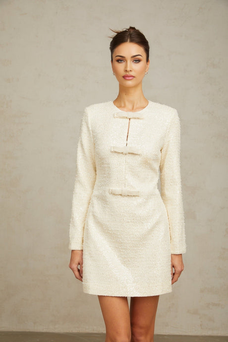 A short white tweed mini dress adorned with shimmering sequins featuring a fitted silhouette and intricate texture