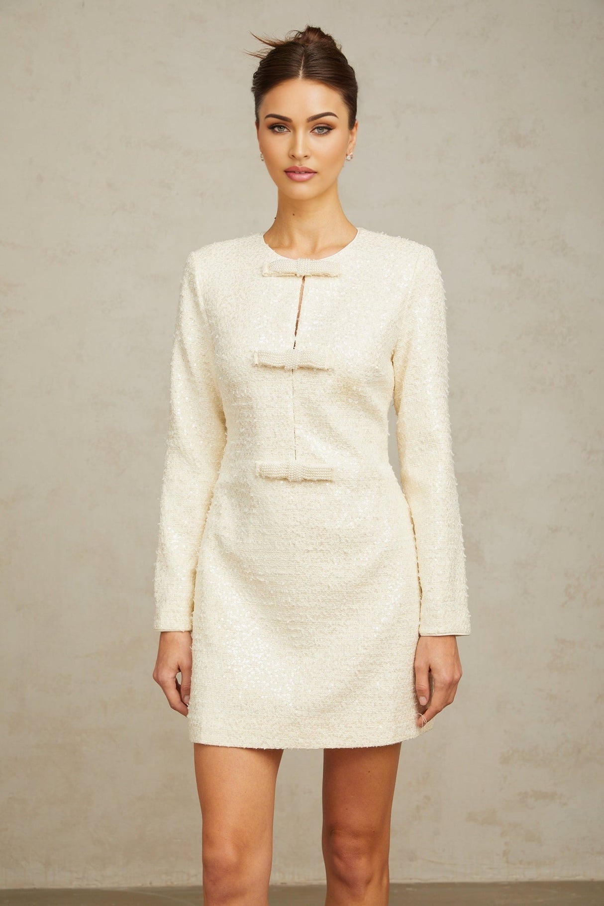 A short white tweed mini dress adorned with sparkling sequins featuring a feminine and elegant design