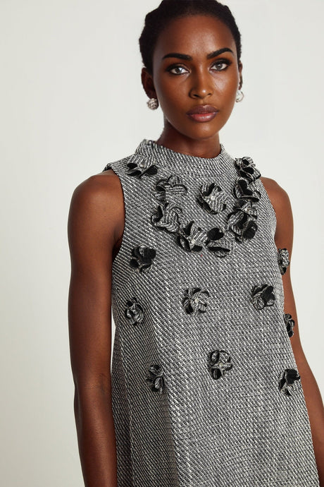 A sleeveless mini dress adorned with faux flowers featuring a floral pattern and short hemline
