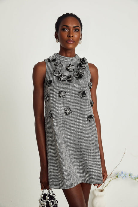 A sleeveless mini dress featuring colorful faux flowers on a light background with a flared skirt and fitted bodice