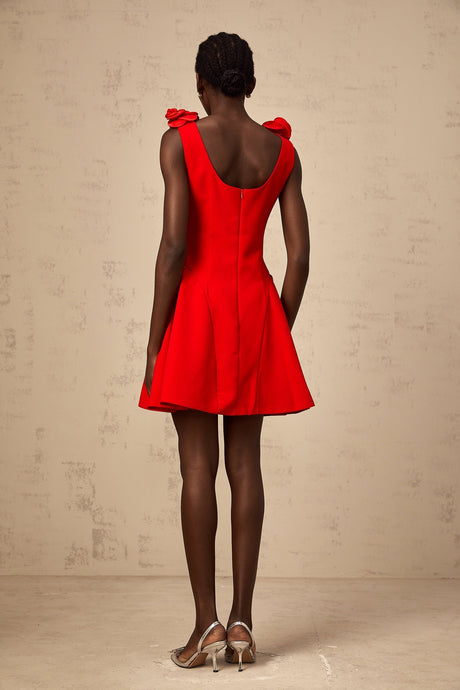 A sleeveless mini dress in bright red with faux flower embellishments on a model against a plain background