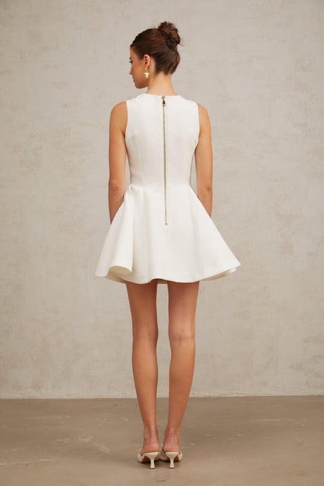 A sleeveless mini dress with a pleated peplum hem named Elise featuring a fitted bodice and flared skirt