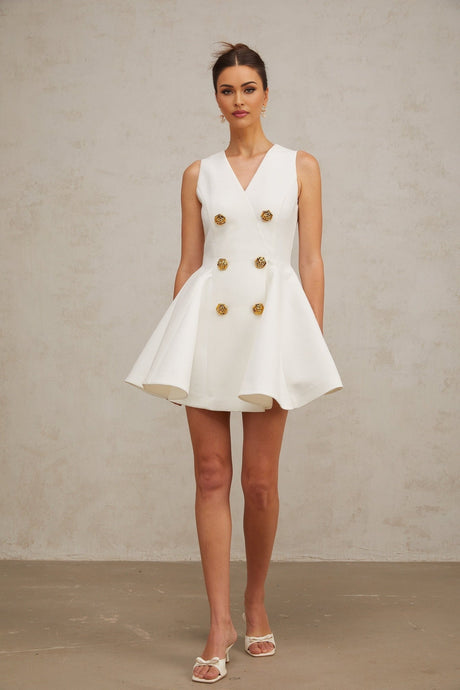 A sleeveless mini dress with a pleated peplum hem named Elise The dress has a fitted bodice and flares out at the waist creating a feminine silhouette