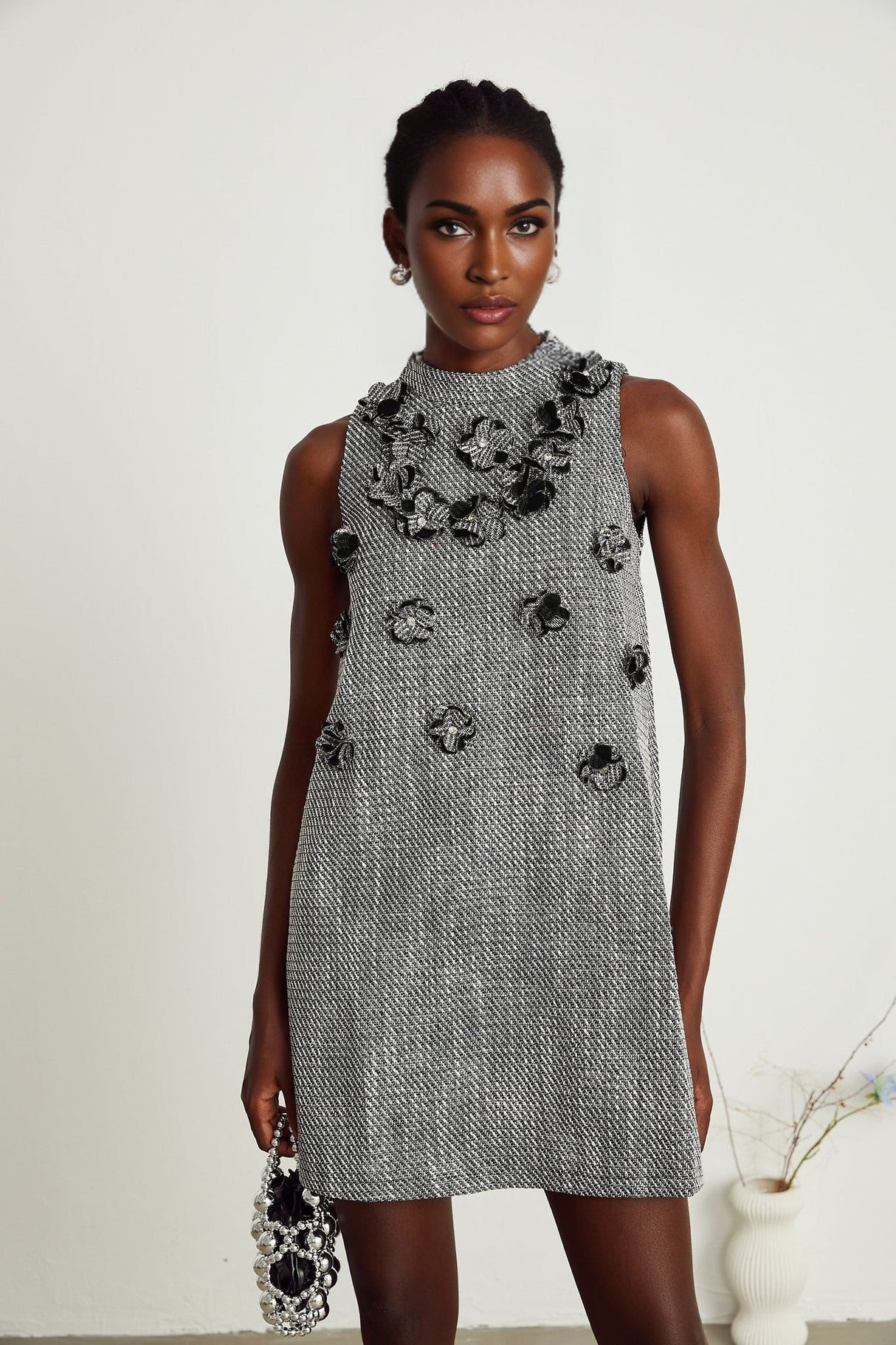 A sleeveless mini dress with colorful faux flowers printed on a light background showcasing the Nadege design