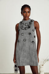 A sleeveless mini dress with colorful faux flowers printed on a light background showcasing the Nadege design