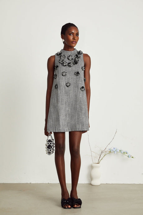 A sleeveless mini dress with faux flower embellishments in a vibrant floral pattern against a light background