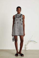 A sleeveless mini dress with faux flowers adorning the fabric showcasing a floral pattern against a light background