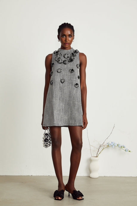 A sleeveless mini dress with faux flowers adorning the fabric showcasing a floral pattern against a light background