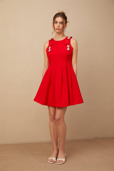 A sleeveless red mini dress with a pleated skirt and a bow detail named Louisa