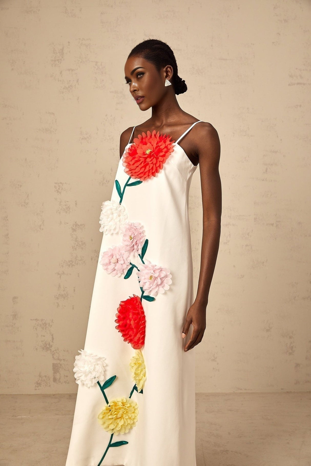 A sleeveless white midi dress with threedimensional petal details covering the bodice and skirt creating a textured floral effect