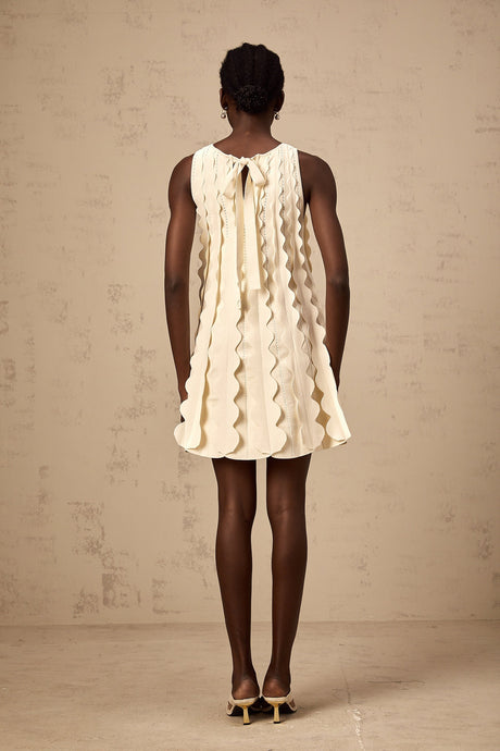 A sleeveless white mini dress with wavy details named Axelle