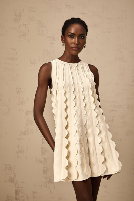 A sleeveless white mini dress with wavy details on a model named Axelle