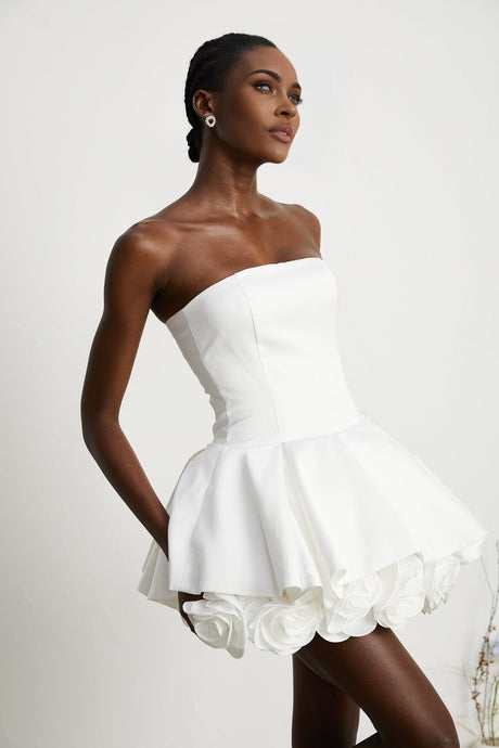 A strapless white mini dress with a corsetstyle bodice adorned with flower petals forming a floral pattern