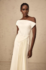 A white asymmetric midi dress with draped fabric details featuring a flowing silhouette and uneven hemline