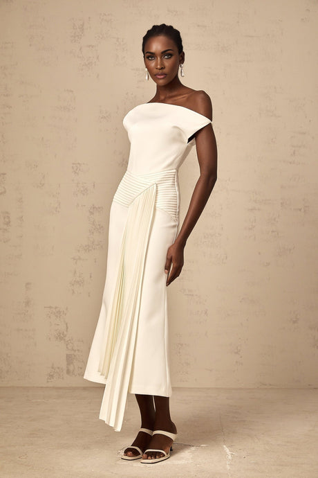 A white asymmetric midi dress with draped fabric details worn by a model standing against a plain background