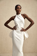 A white bandage dress with a large oversized bow detail named Capucine featuring a formfitting silhouette and sleeveless design