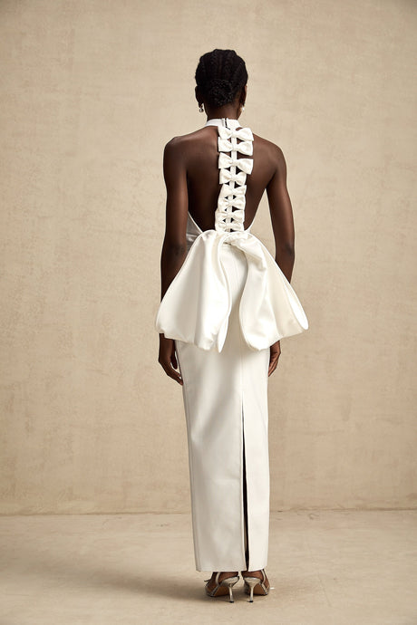 A white bandage dress with an oversized bow accent named Capucine featuring a formfitting silhouette and exaggerated bow detail